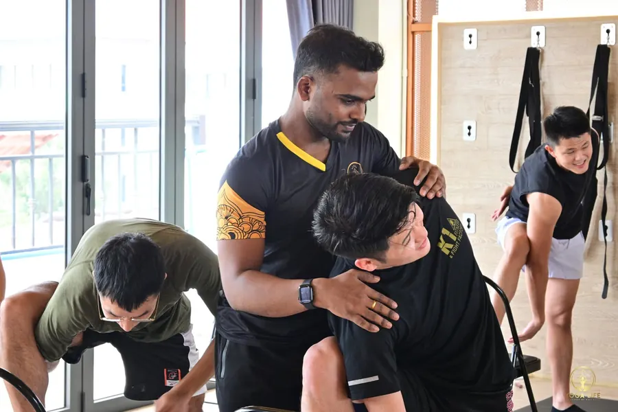 A teacher giving a hands-on adjustment to a student in a class